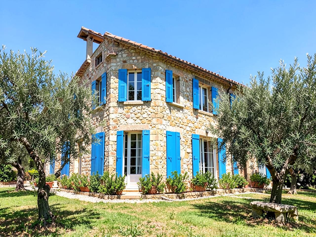 Villa en pierre aux volets bleus entourée d'oliviers